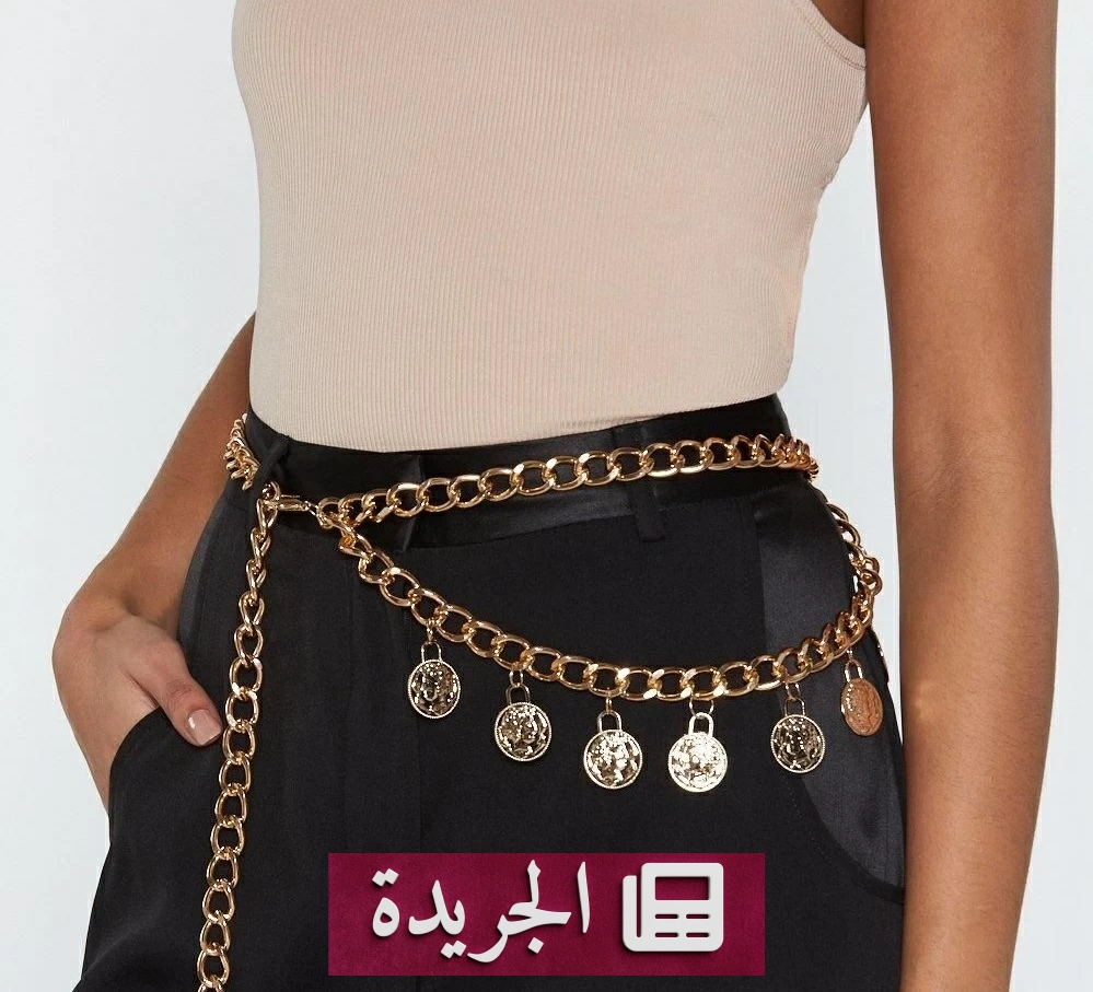 أحزمة معدنية متنوعة تعرض على منصة أزياء، بما في ذلك سلاسل ذهبية وفضية وأحزمة مزينة بالأحجار