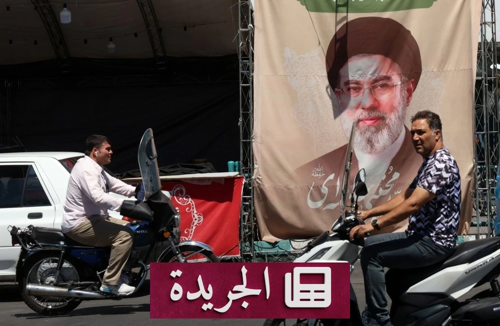 إيرانيون يمرون بدراجاتهم بجانب لوحة إعلانية تحمل صورة المرشد الإيراني علي خامنئي في طهران